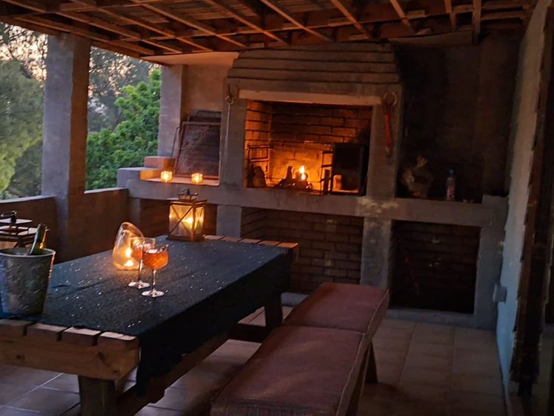 Covered outdoor patio featuring a built-in brick fireplace, tiled flooring, and exposed timber ceiling beams, ideal for evening entertaining.
