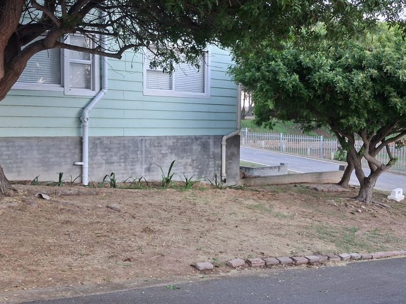 Front exterior view of the property featuring weatherboard cladding, concrete foundation, and established trees on a corner lot.