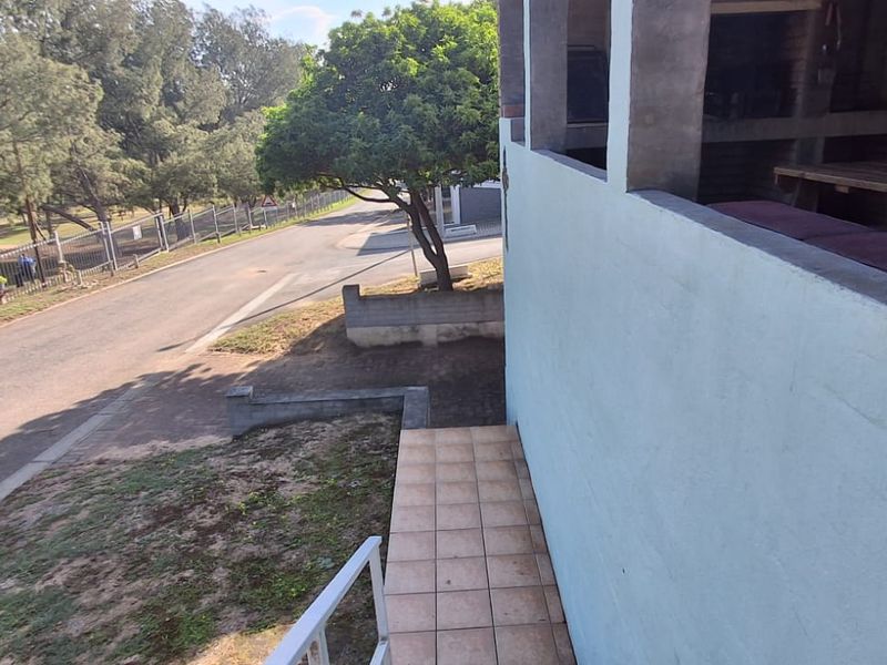 An elevated patio area featuring tiled flooring, a built-in braai, and views overlooking the street and surrounding neighborhood.
