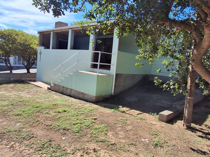 Front exterior view of the property featuring a covered porch area with exposed structural elements and a concrete staircase with metal handrails.