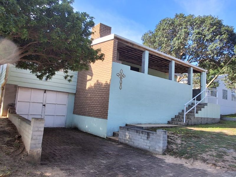 Front exterior view of a house featuring a brick chimney, covered patio, garage, and concrete staircase leading to the entrance.