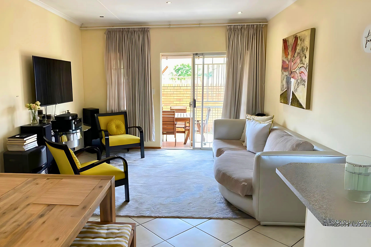 A bright living room featuring tiled flooring, recessed ceiling lighting, and sliding glass doors that provide direct access to an outdoor patio area.
