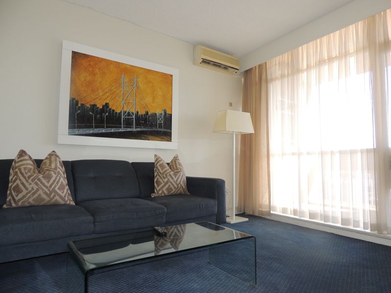 A comfortable living room featuring wall-to-wall carpeting, a wall-mounted air conditioning unit, and large sliding glass doors that provide ample natural light.