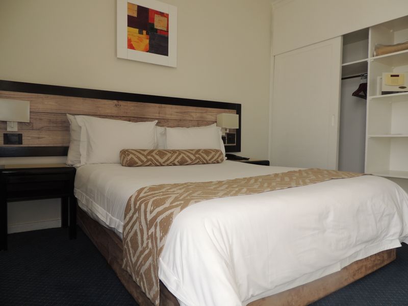 A well-maintained bedroom featuring a built-in wardrobe with integrated shelving and a modern wall-mounted headboard design.