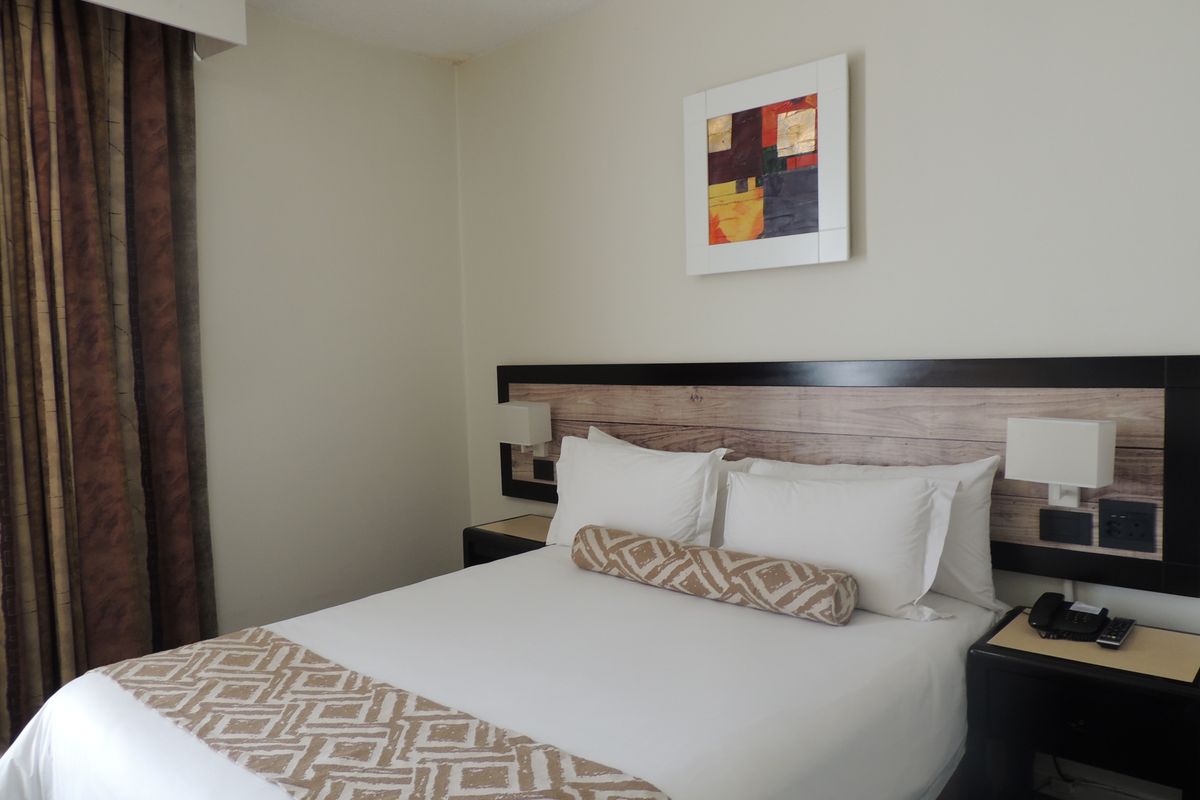 A well-maintained bedroom featuring a built-in headboard with integrated lighting and bedside surfaces, offering a clean and functional sleeping space.