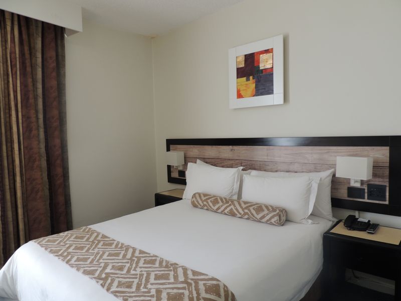 A well-maintained bedroom featuring a built-in headboard with integrated lighting and bedside surfaces, offering a clean and functional sleeping space.