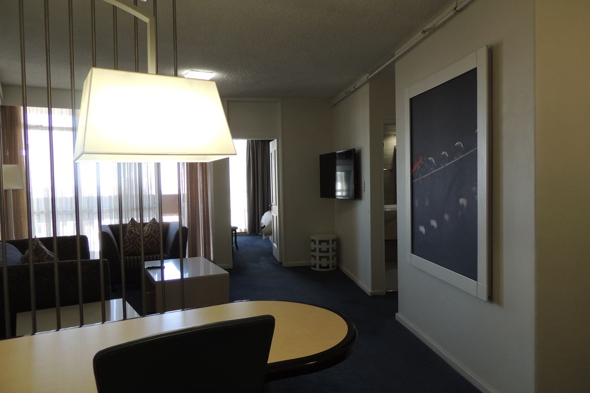 A living area featuring a metal room divider, built-in lighting, and a wall-mounted television, providing a functional and connected space.