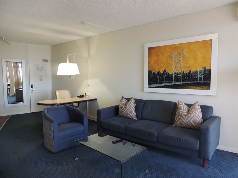 A comfortable living area featuring a built-in desk, wall-mounted lighting, and a full-length mirror, providing a functional and well-lit space.