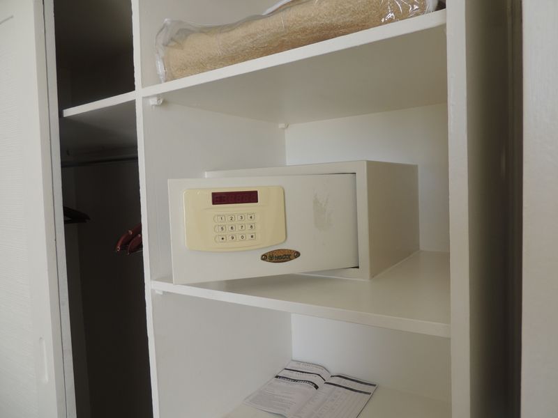 A built-in bedroom cupboard featuring integrated shelving and a secure digital wall safe.