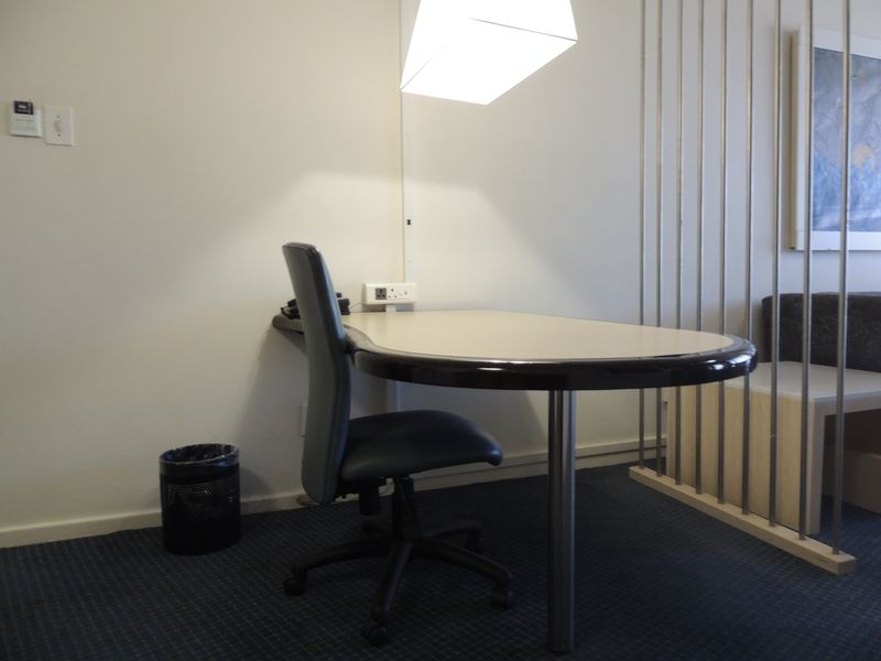 A functional office space featuring a built-in desk, carpeted flooring, and modern pendant lighting, suitable for a dedicated workspace.