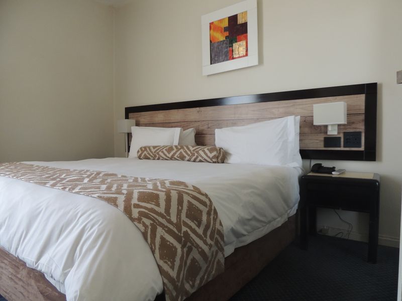 A well-maintained bedroom featuring a custom built-in headboard with integrated lighting and bedside electrical points.