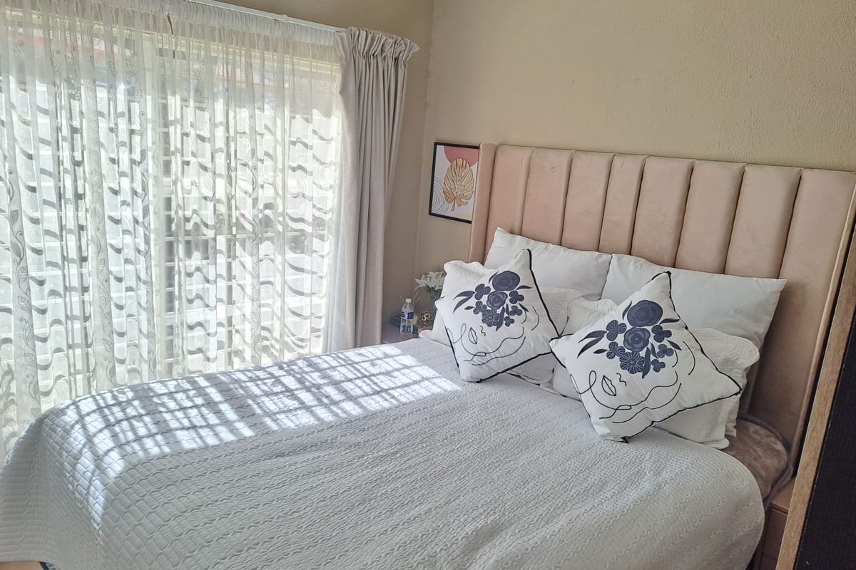 A bedroom featuring a large sliding glass door with sheer curtains, providing natural light and access to the exterior.