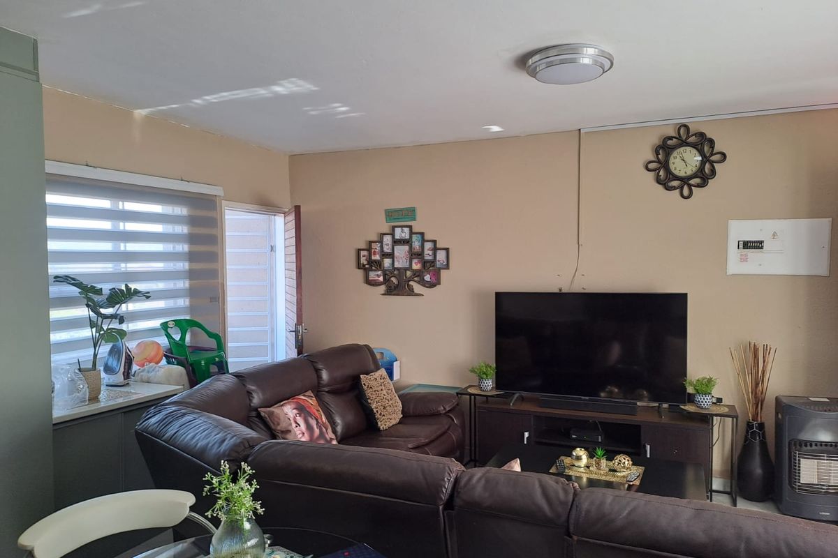 A comfortable living room featuring neutral wall tones, zebra blinds, and a built-in gas heater, providing a functional and cozy space.