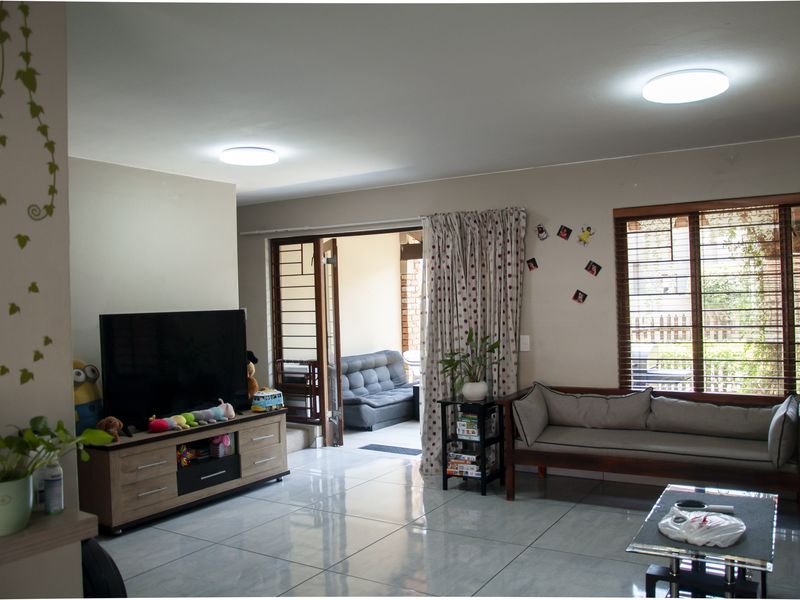 Spacious living room featuring large format floor tiles, flush-mount ceiling lighting, and direct access to an outdoor patio area through sliding doors.