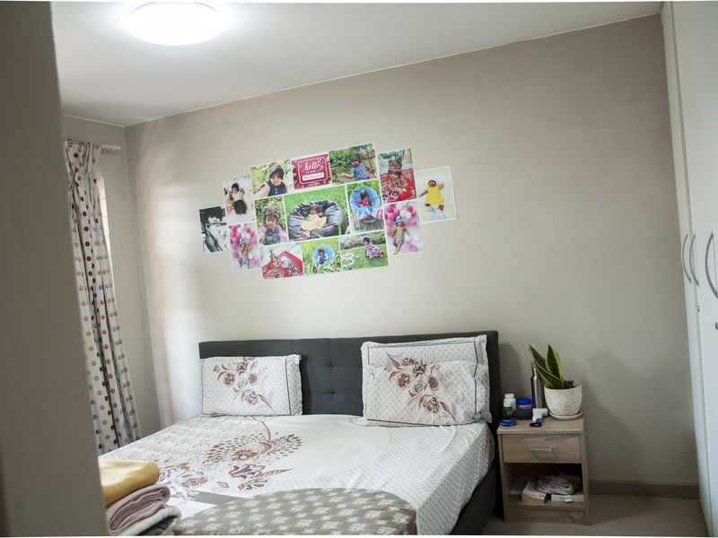 A well-maintained bedroom featuring neutral wall tones, built-in wardrobe storage, and carpeted flooring, offering a comfortable and functional living space.