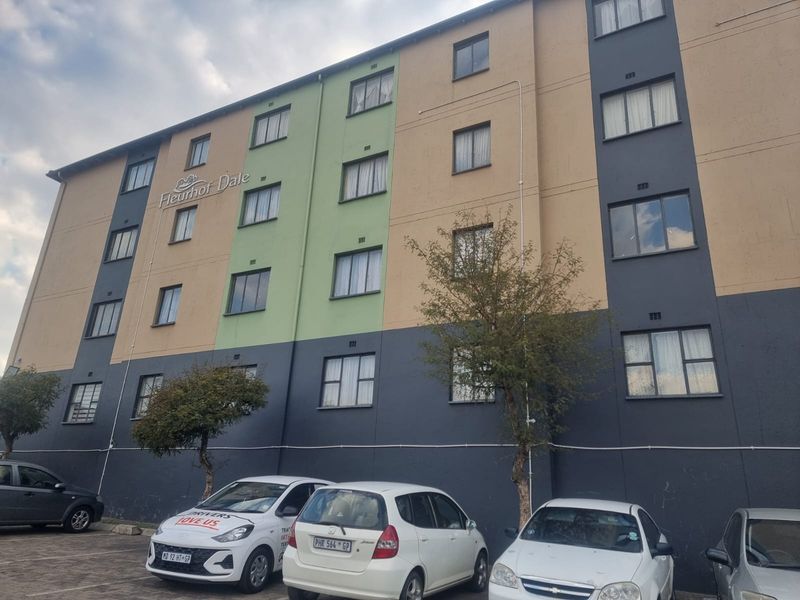 Exterior view of the Fleurhof Dale apartment complex, featuring a multi-story facade with paved parking area at the front.