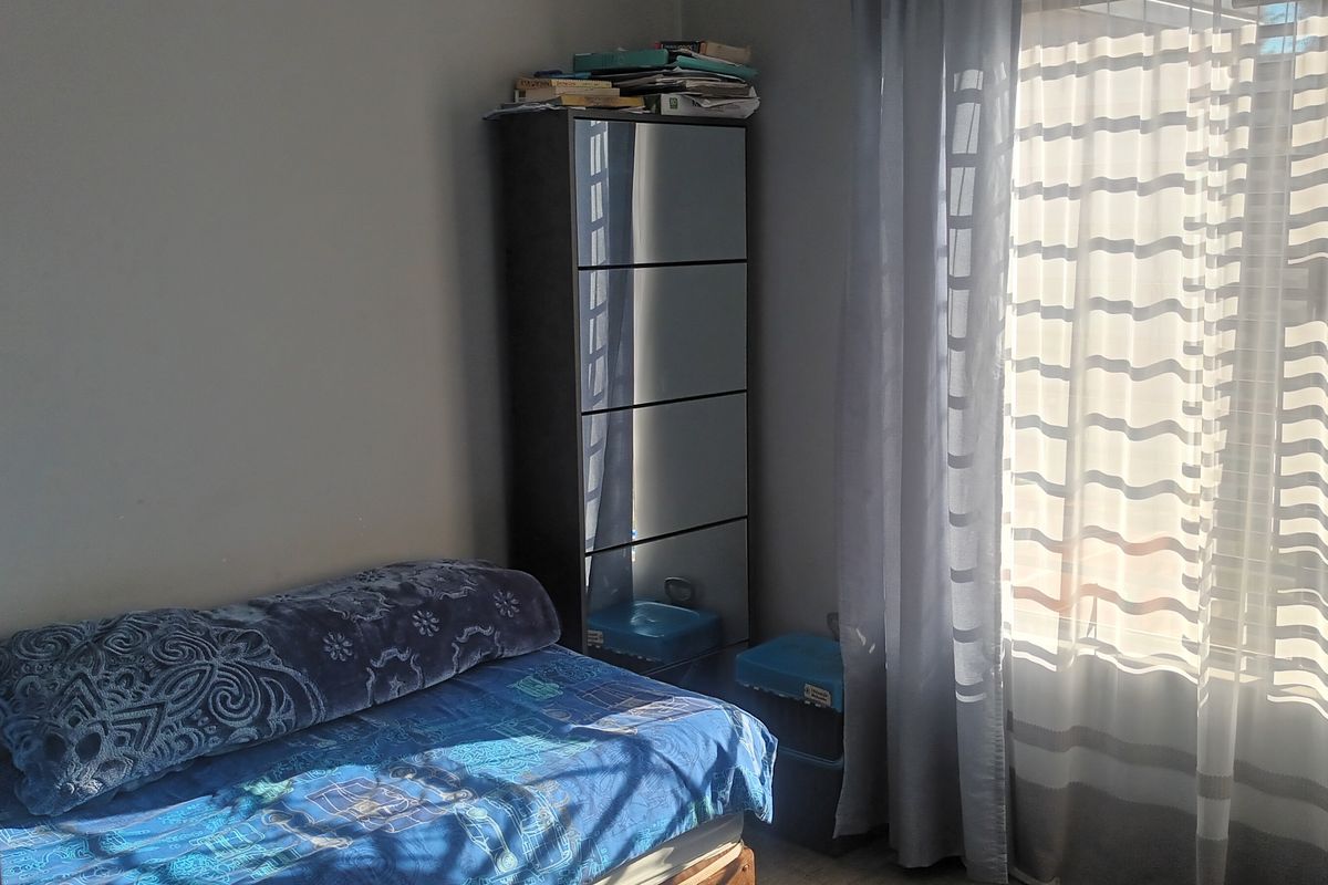 A standard bedroom featuring a window with installed curtain rails, providing natural light to the space.