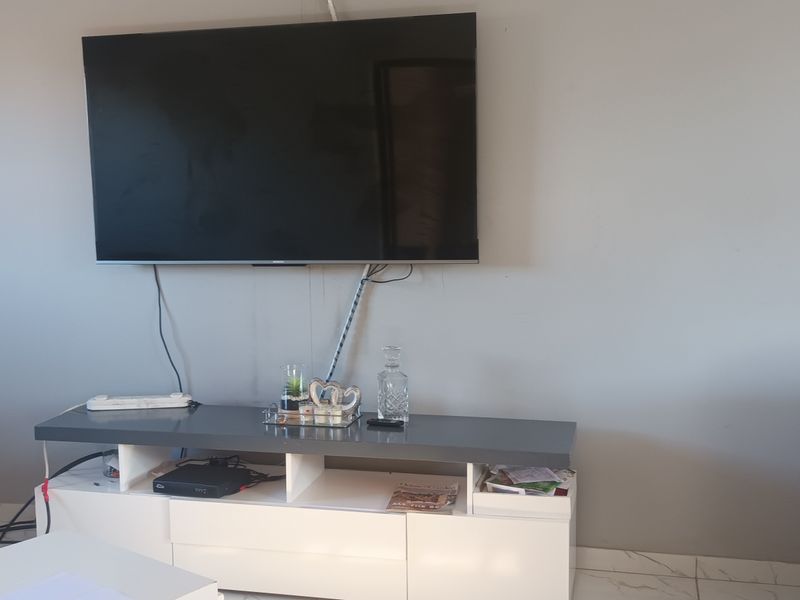 A living room area featuring tiled flooring and a wall-mounted television setup.