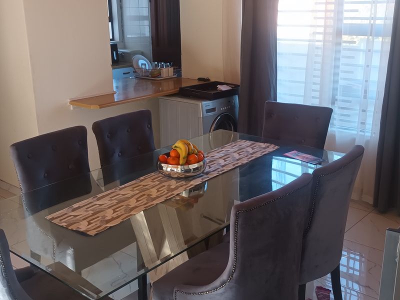 Dining area featuring tiled flooring and a breakfast bar, with an adjacent kitchen space visible in the background.