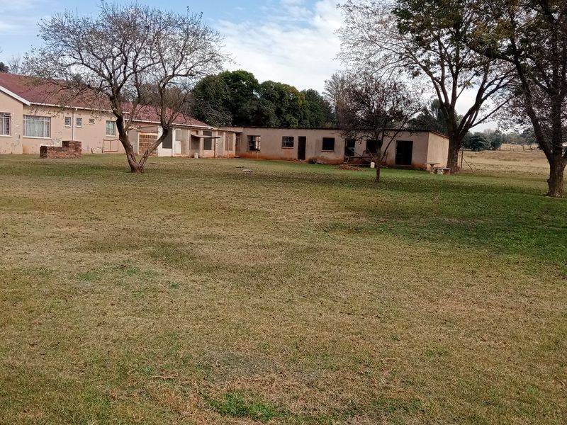 A view of the rear farm property featuring a large lawn area and multiple outbuildings with traditional brick and tile construction.