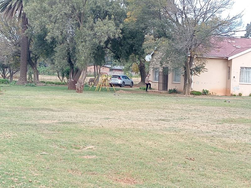 Rear view of the farm property featuring a large garden area, metal roof, and exterior wall finishes.