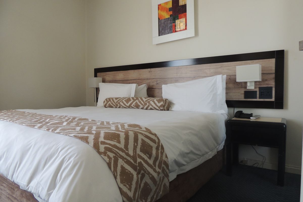 A well-maintained bedroom featuring a custom built-in headboard with integrated bedside lighting and convenient electrical power points.