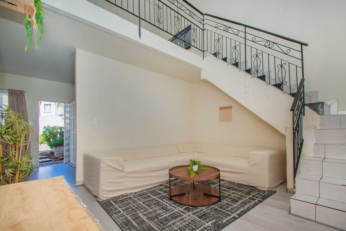 A living area featuring a staircase with wrought iron railings and tiled steps, providing access to the upper level of the apartment.