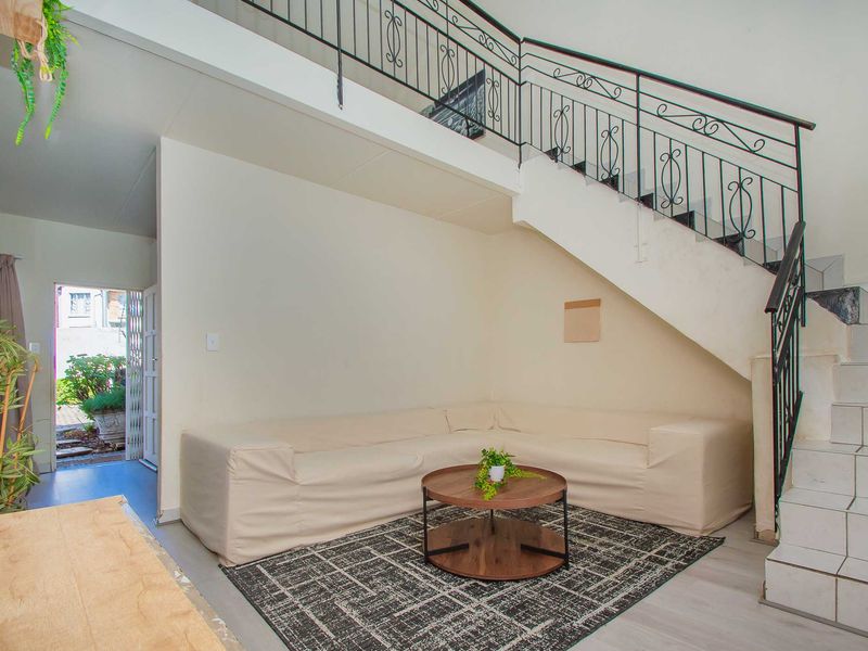 A living area featuring a staircase with wrought iron railings and tiled steps, providing access to the upper level of the apartment.