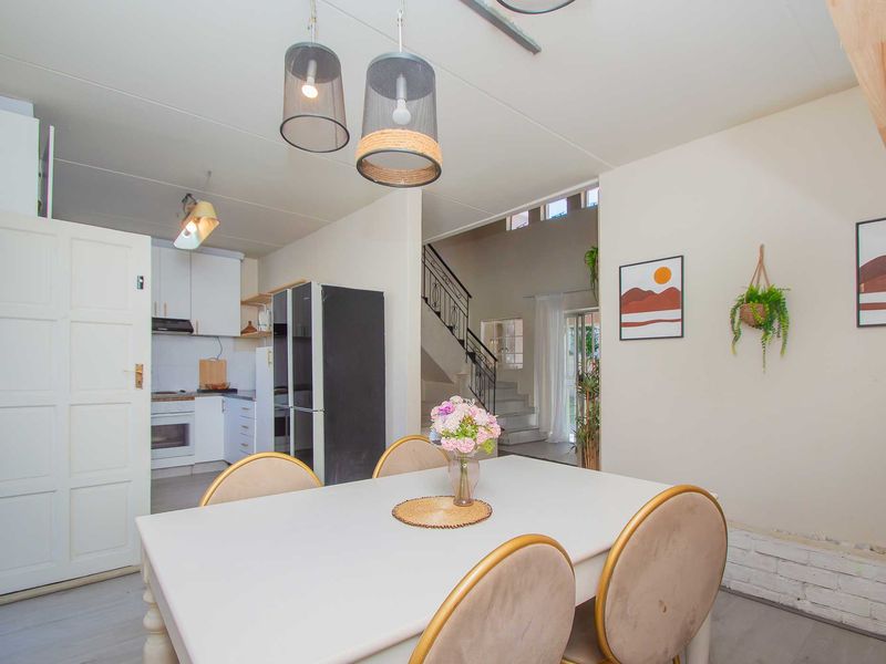Open plan dining area featuring modern pendant lighting, adjacent to a functional kitchen and a staircase leading to the upper level.