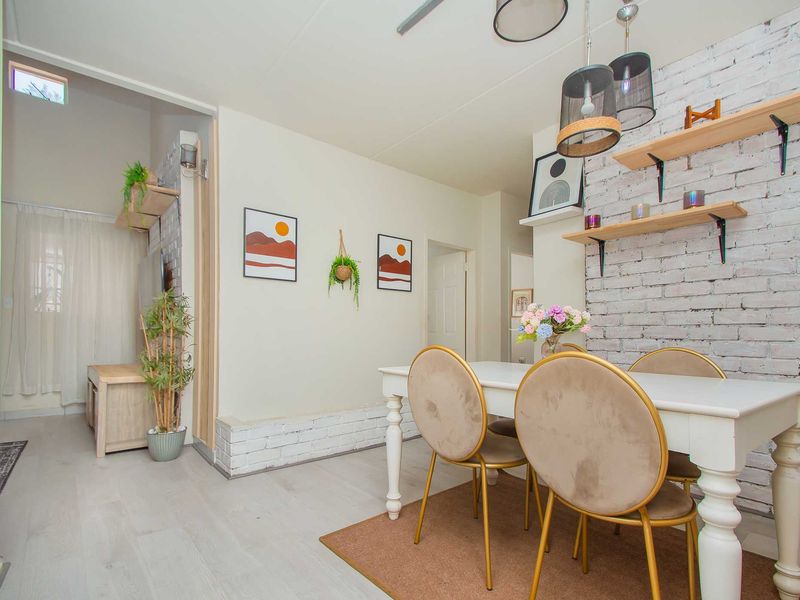 Open plan living and dining area featuring exposed brick wall accents, laminate flooring, and modern pendant lighting.