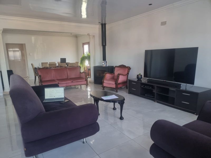 Spacious open-plan living area featuring glossy floor tiles, a modern freestanding fireplace, and recessed ceiling lighting, creating a bright and functional living space.