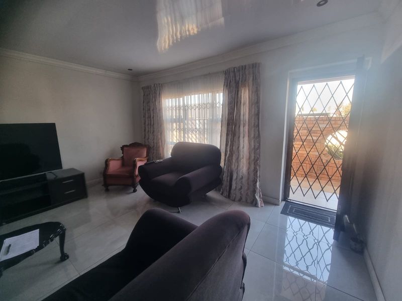 A living room featuring polished tiled flooring, recessed ceiling lights, and a security gate leading to the exterior.