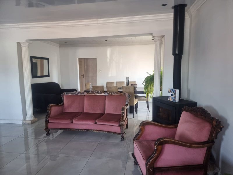 Open-plan living and dining area featuring tiled flooring, decorative columns, and a modern freestanding fireplace.