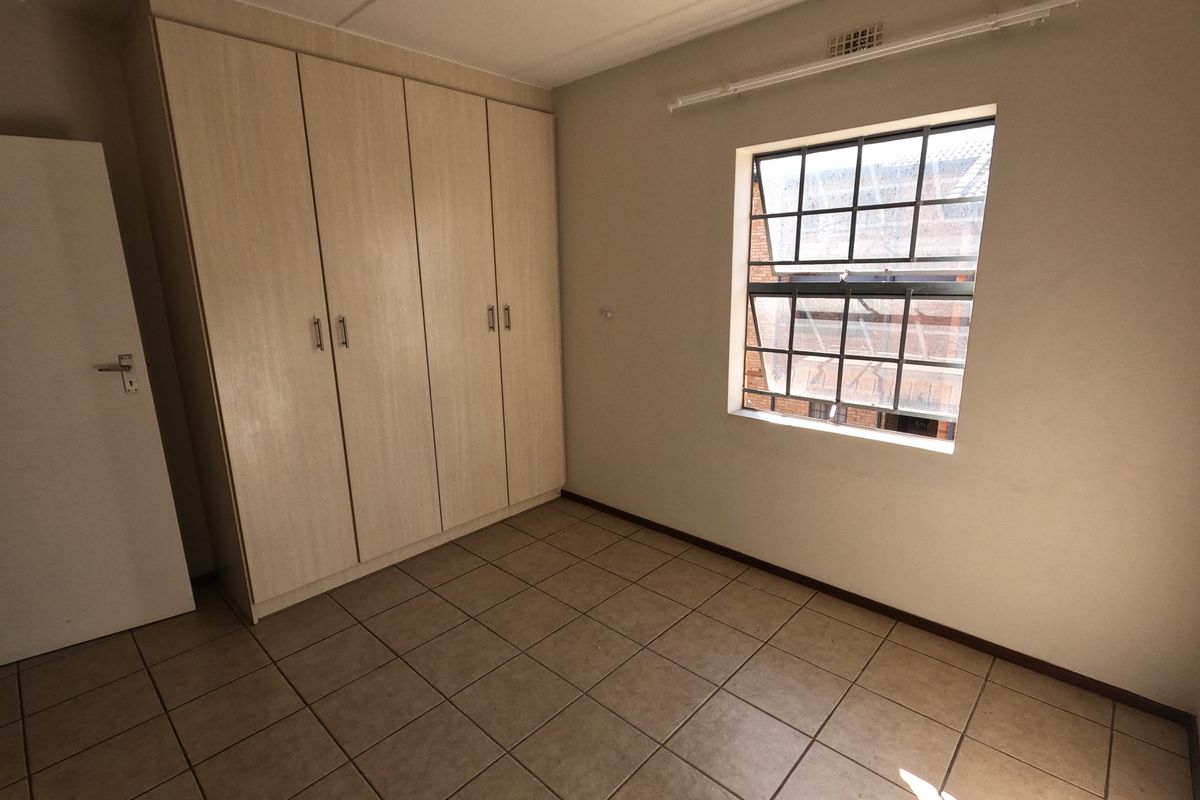 An empty bedroom featuring tiled flooring and built-in cupboards, providing a clean and functional space ready for personalization.