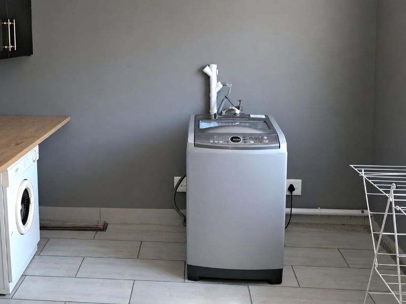 A functional laundry room featuring tiled flooring, built-in cabinetry, and dedicated plumbing and electrical connections for laundry appliances.