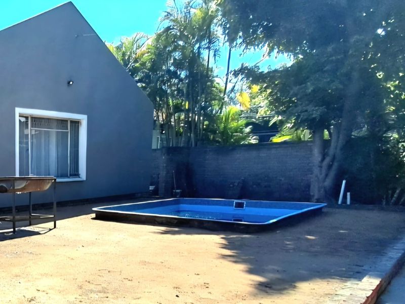 Rear garden area featuring a swimming pool and boundary wall, requiring landscaping to enhance the outdoor living space.