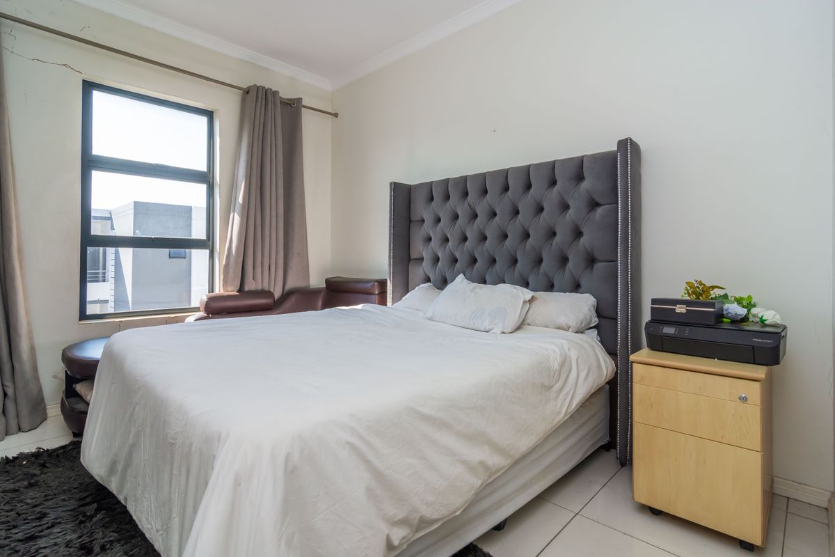 A bedroom featuring tiled flooring and an aluminium window frame, showing a visible wall crack above the window frame.