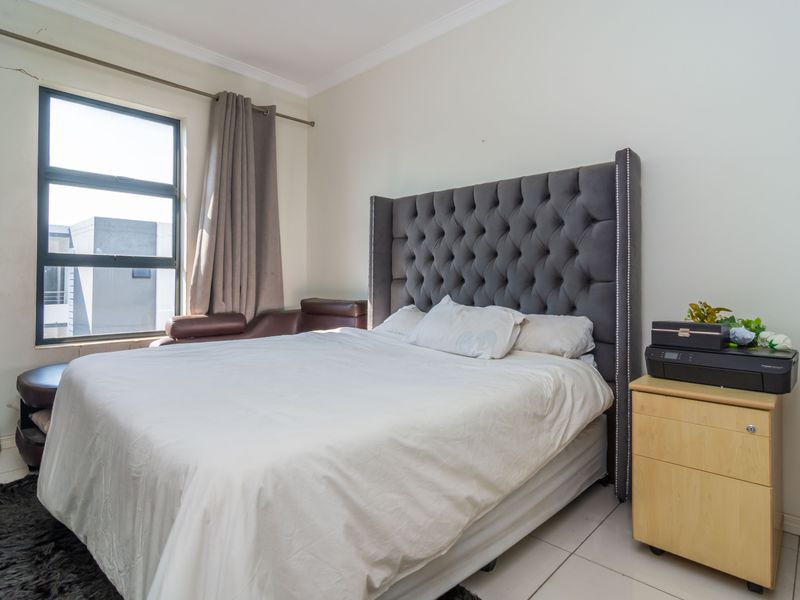 A bedroom featuring tiled flooring and an aluminium window frame, showing a visible wall crack above the window frame.