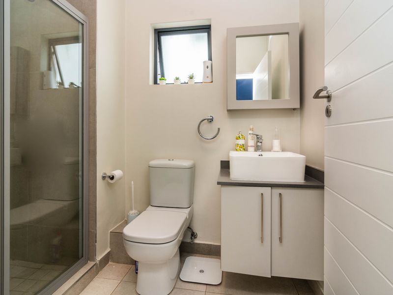 A modern, well-maintained bathroom featuring a glass-enclosed shower, a vanity unit with a basin, and neutral tiling.