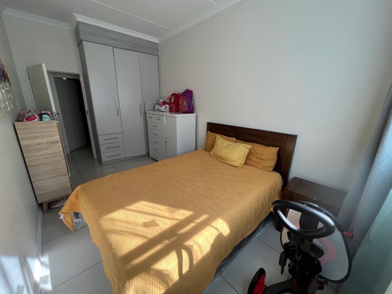 A well-maintained bedroom featuring neutral tiled flooring, built-in wardrobe storage, and coving detail.