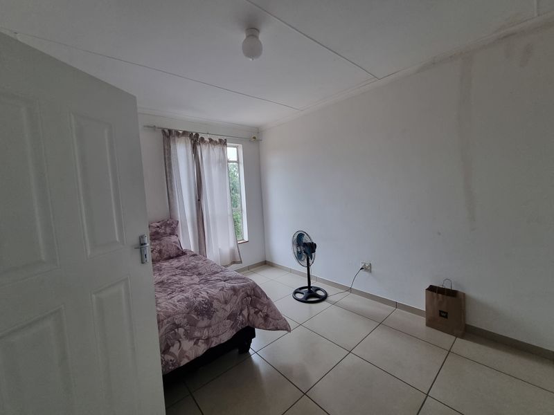 A bedroom featuring tiled flooring and a window with curtain rods. The room requires cosmetic attention to the walls and ceiling.