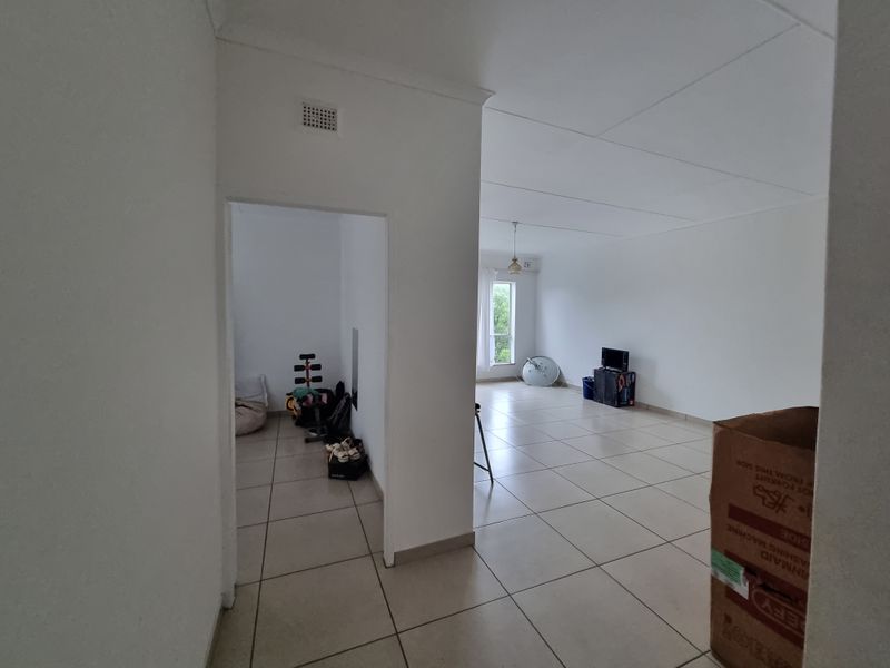 An open-plan living area featuring neutral tiled flooring and white walls, offering a blank canvas for interior design and furniture placement.