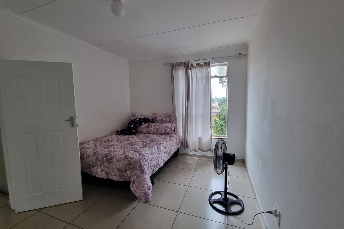 A simple bedroom featuring tiled flooring and a window with a curtain rail, requiring minor cosmetic updates to the wall finishes.