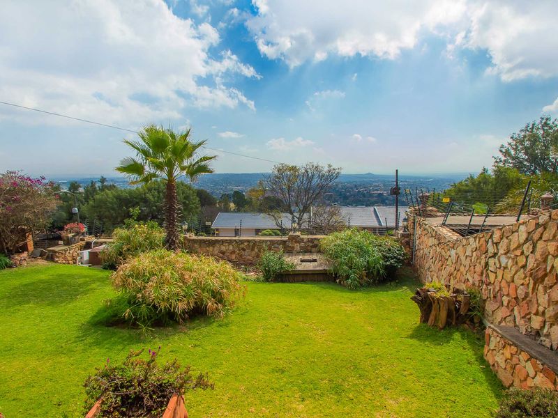 A well-maintained rear garden featuring a stone retaining wall, electric fencing, and expansive views over the surrounding area.