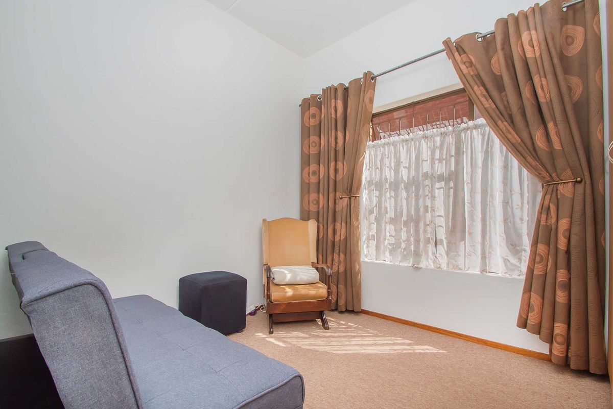 A bedroom featuring carpeted flooring and a window with installed curtain rods, providing natural light to the space.
