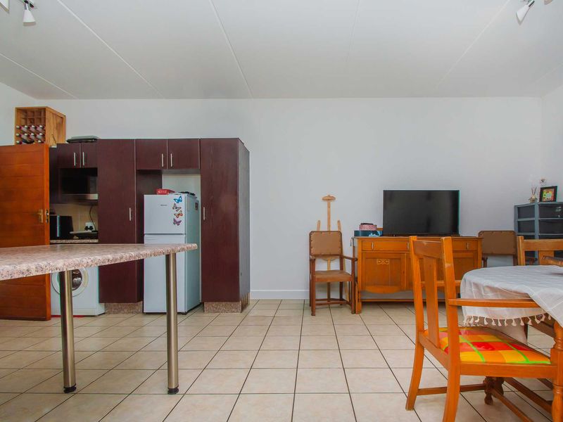 Open plan living and kitchen area featuring tiled flooring, built-in dark wood cabinetry, and a functional breakfast counter.