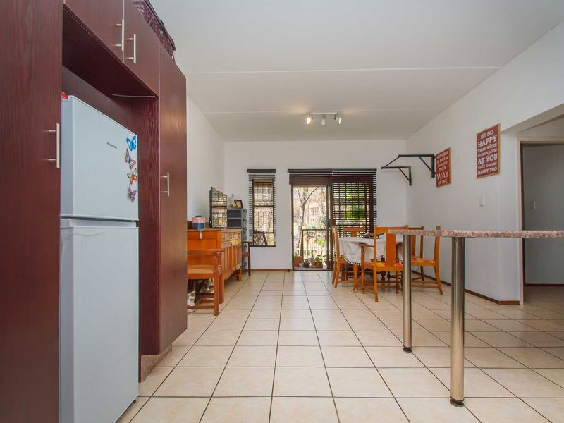 Open-plan living and kitchen area featuring tiled flooring, built-in cabinetry, a breakfast counter, and sliding door access to an outdoor balcony.