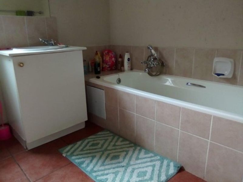 A functional bathroom featuring a tiled bathtub surround, vanity cabinet with basin, and neutral wall finishes.