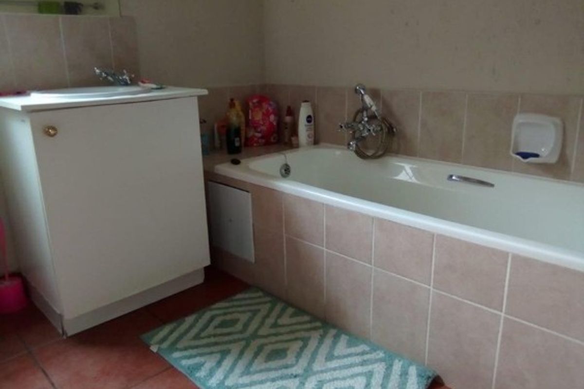 A functional bathroom featuring a tiled bathtub surround, vanity cabinet with basin, and neutral wall finishes.