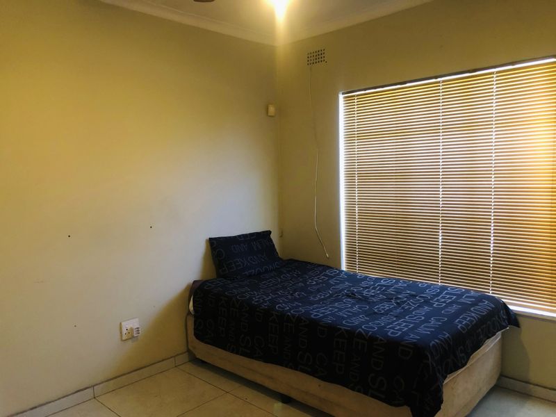 A bedroom featuring tiled flooring and venetian blinds, requiring minor wall repairs and a fresh coat of paint to improve its overall condition.